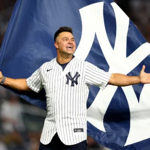 Nick Swisher holding a New York Yankees flag with his arms open wide